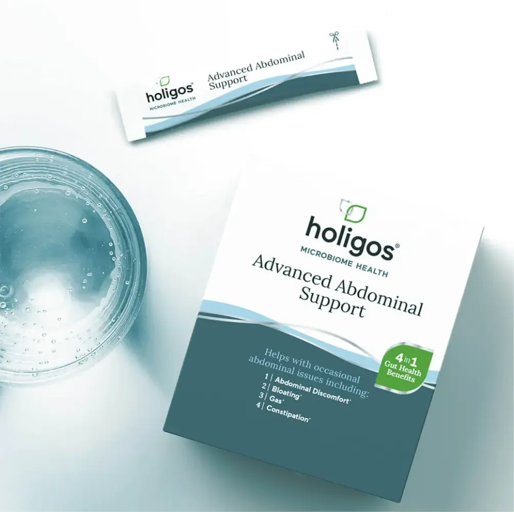 Holigos Advanced Abdominal Support box and stick pack next to a glass of water, seen from above